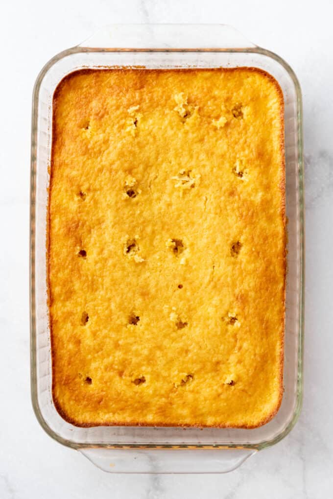 A yellow cake with holes poked into it.