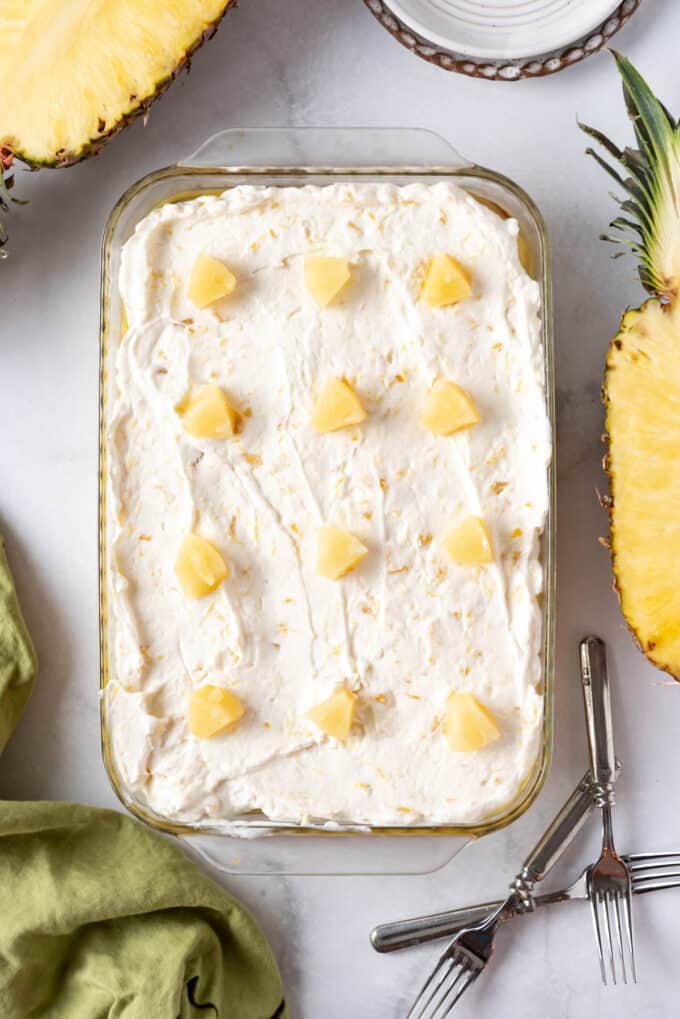 A pineapple pork cake with canned pineapple chunks on top of whipped cream.