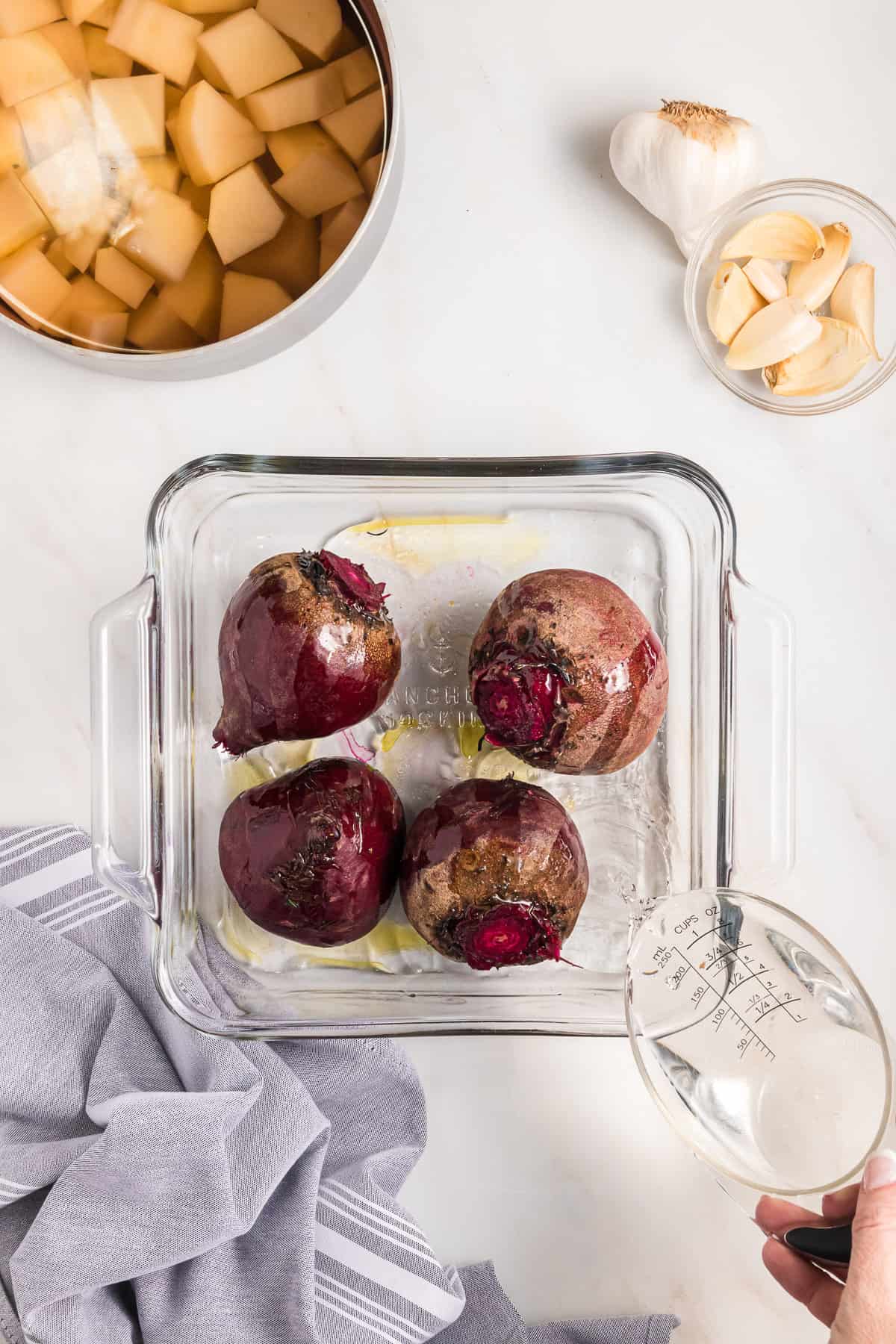 Prepping beets for roasting in the oven in a glass dish.