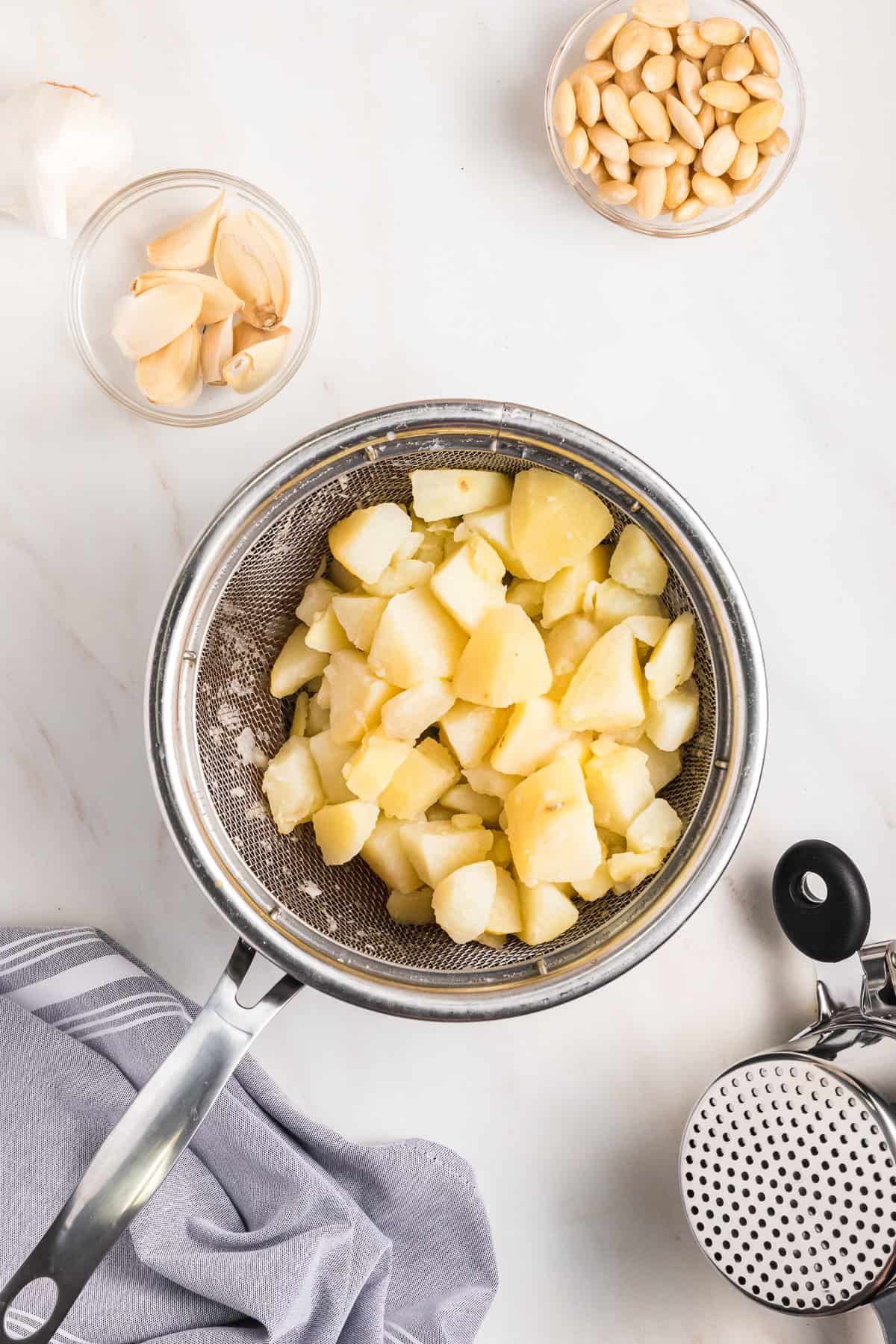 Boiled potatoes draining in a colander over a pot.