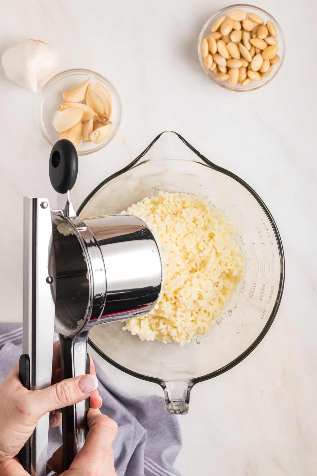 Ricing boiled potatoes into a glass bowl.