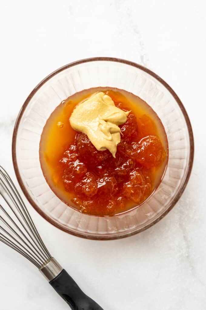 Apricot jam and mustard in a glass bowl.