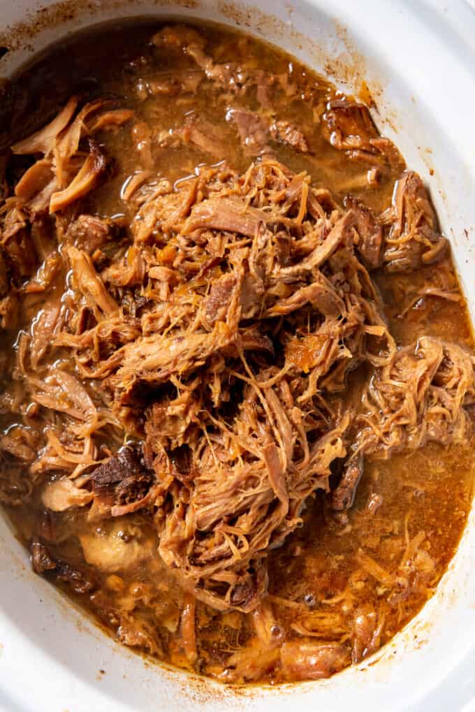 A close image of shredded pulled pork in an apricot sauce in a slow cooker.