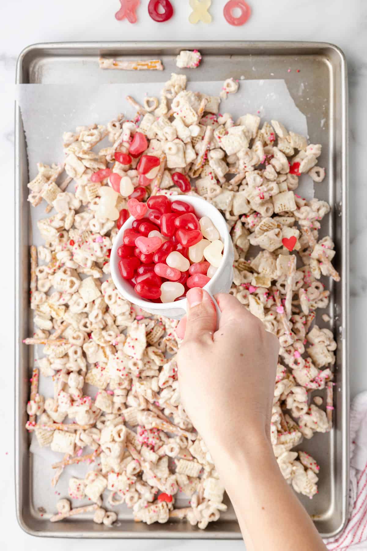 Adding Valentine's Day candy to chex mix.