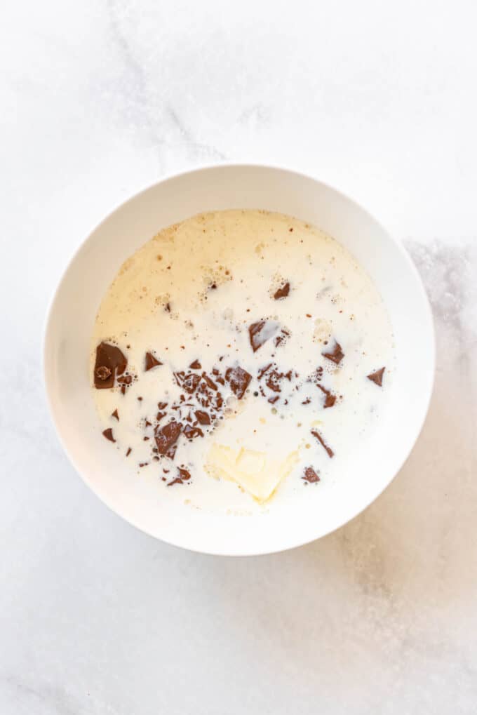 Pouring hot cream over chopped chocolate and butter in a bowl to make truffle centers.
