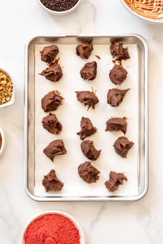Mounds of chocolate ganache on a baking sheet lined with parchment paper.