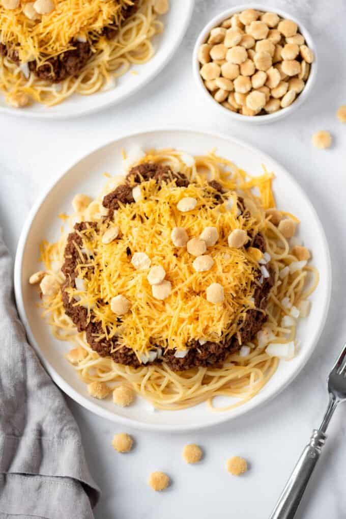 A large plate of spaghetti noodles with Cincinnati chili, onions, and cheddar cheese.