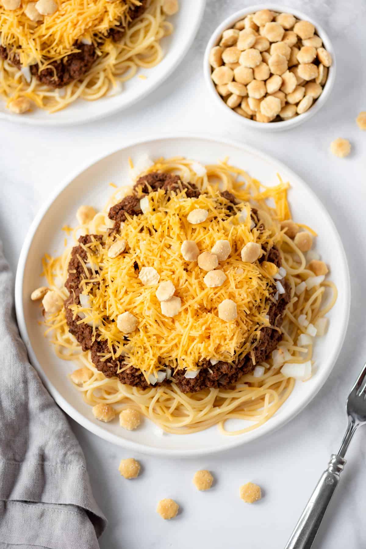 A large plate of spaghetti noodles with Cincinnati chili, onions, and cheddar cheese.