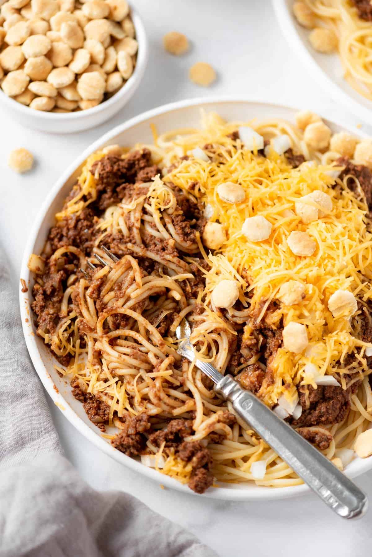 A plate of 4-way Cincinnati chili with a fork in it.