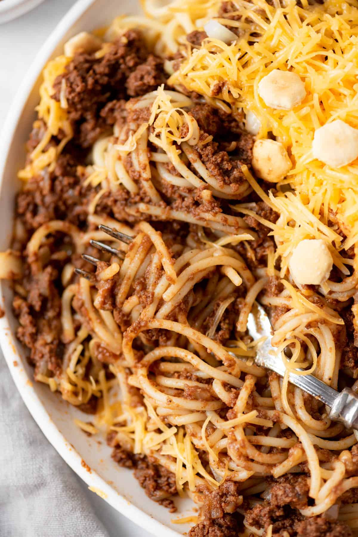 A close image of a fork with a twirl of spaghetti noodles and Cincinnati chili sauce.