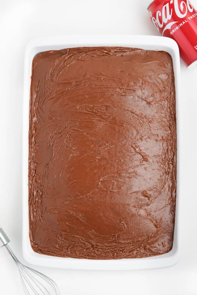 A frosted coca cola cake in a white rectangular baking dish.