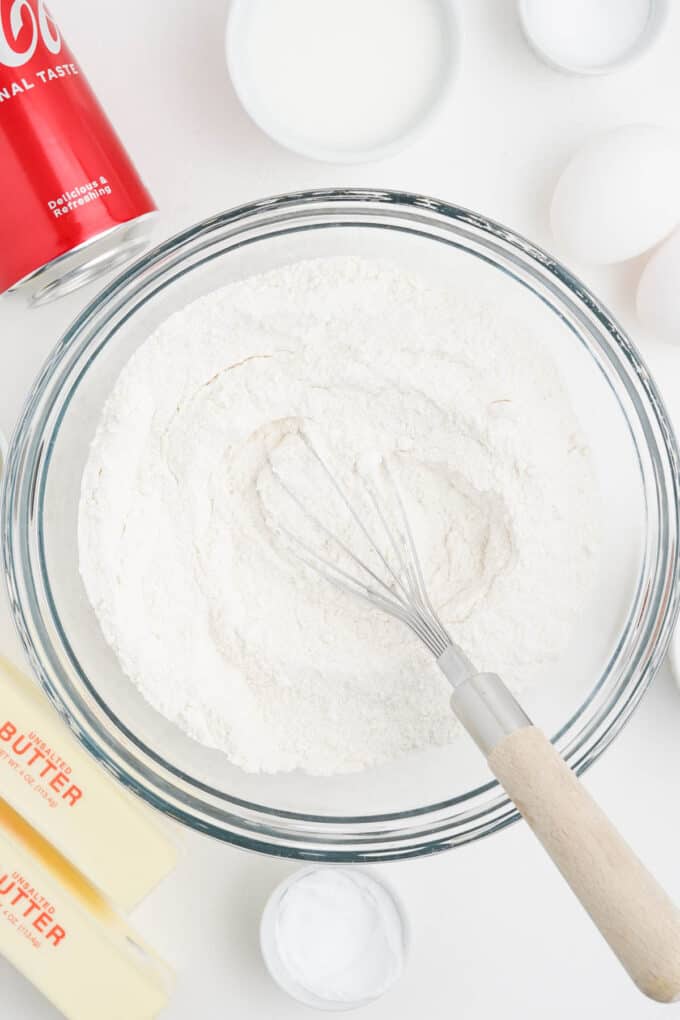 Whisking dry ingredients together in a large glass bowl.