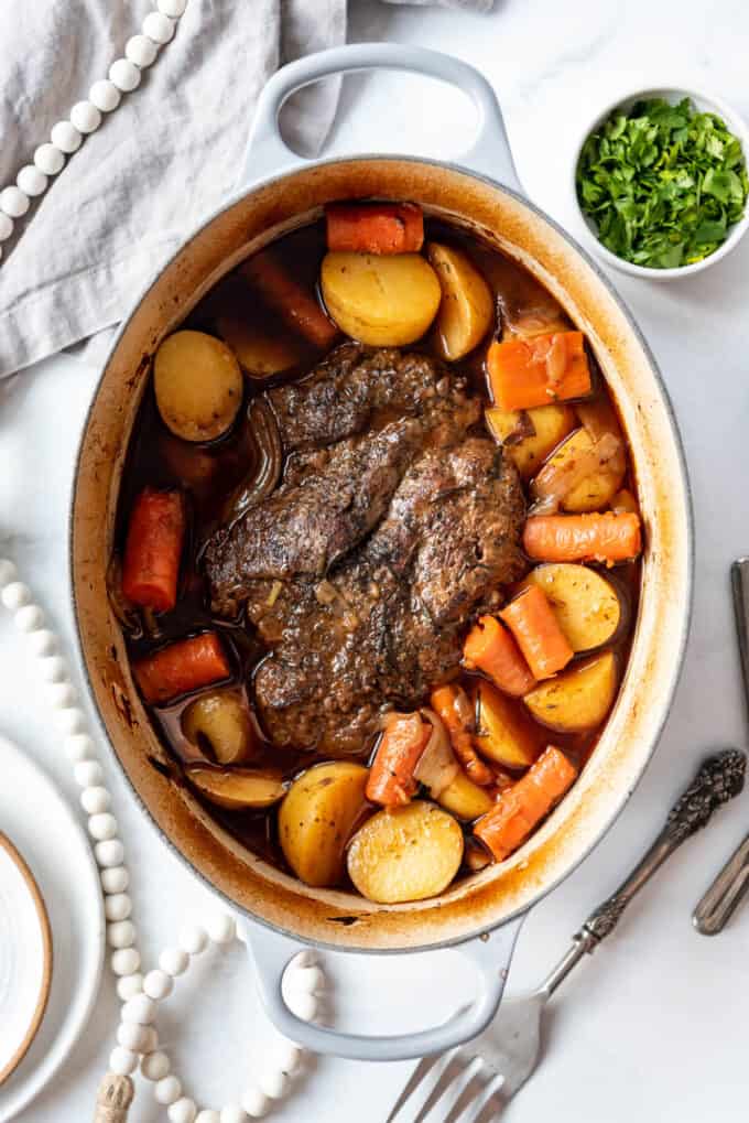 A finished pot roast with vegetables in a Dutch oven.