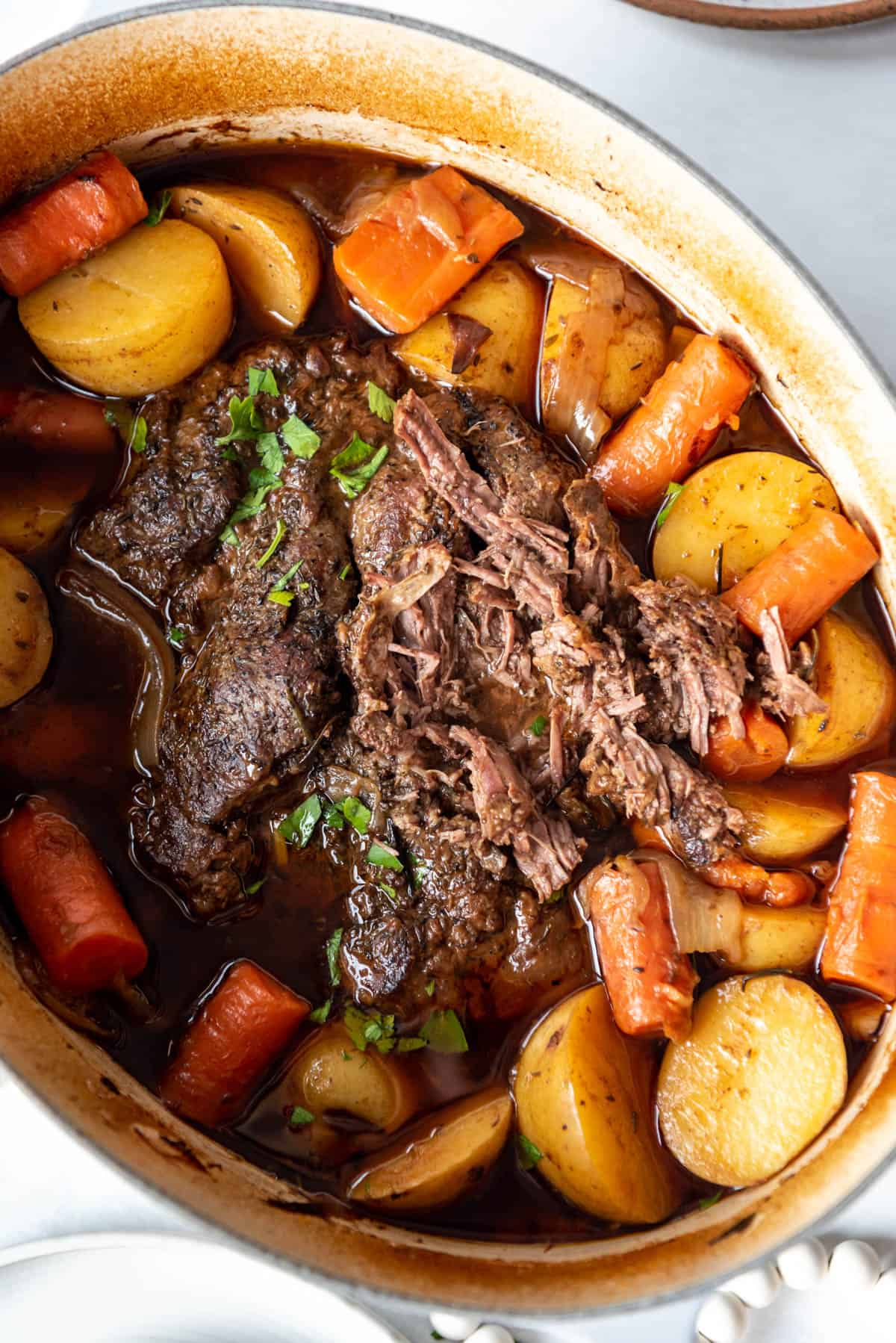 A large 9-quart Dutch oven with roasted carrots, potatoes, and pot roast.
