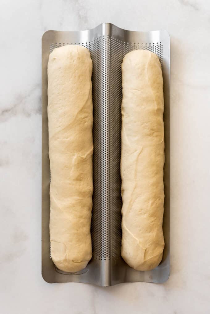 Two unbaked loaves of bread on a French bread pan.
