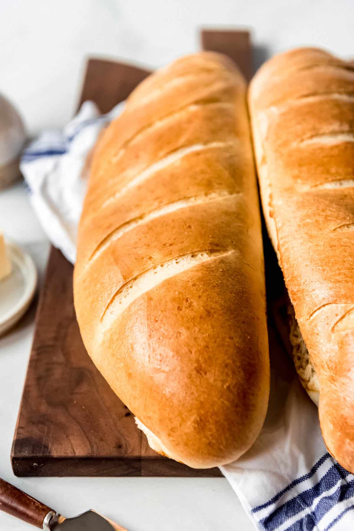 Loaves of crusty fresh French bread on a wooden cutting board.