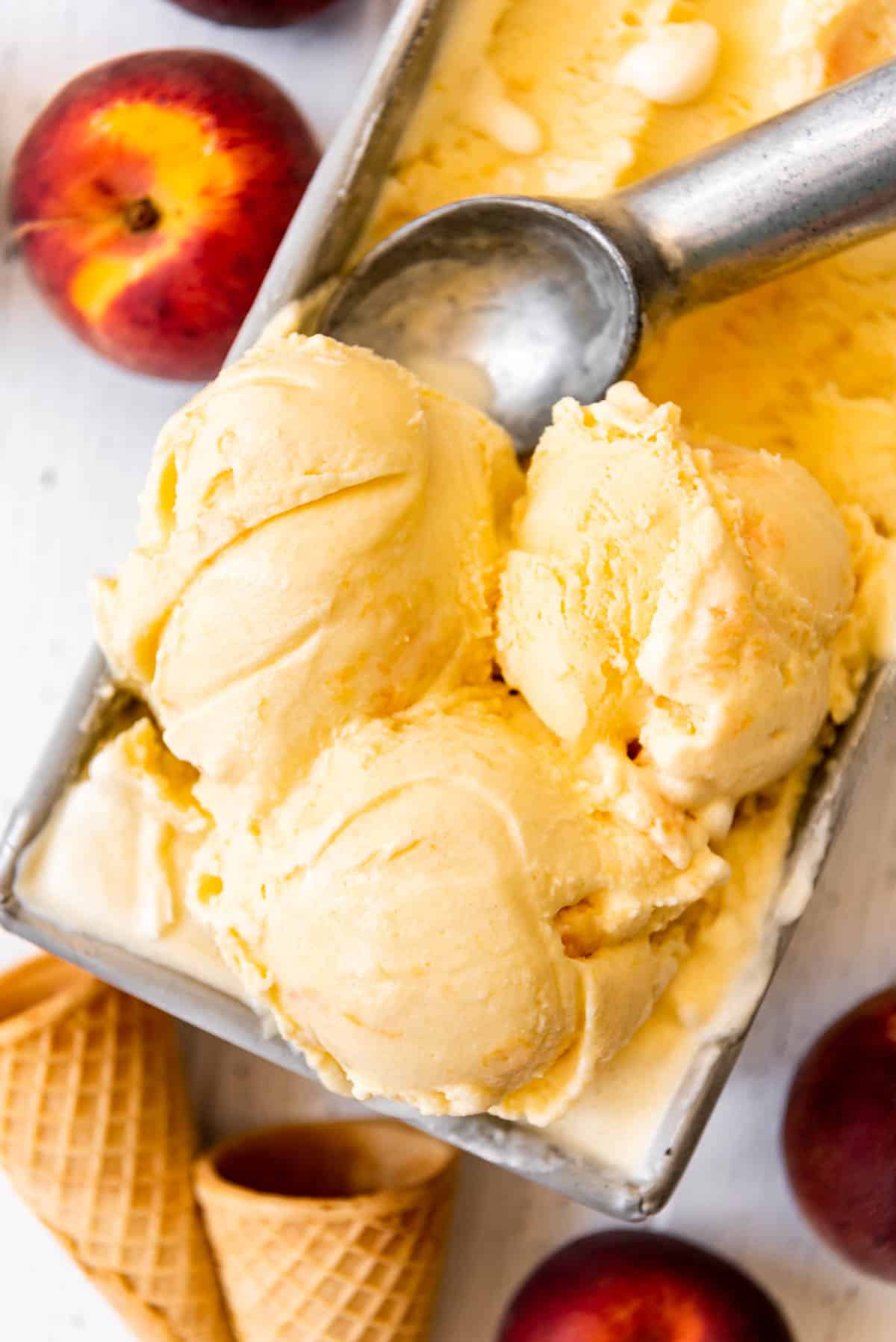 An overhead image of three scoops of peach ice cream in top of the ice cream container.