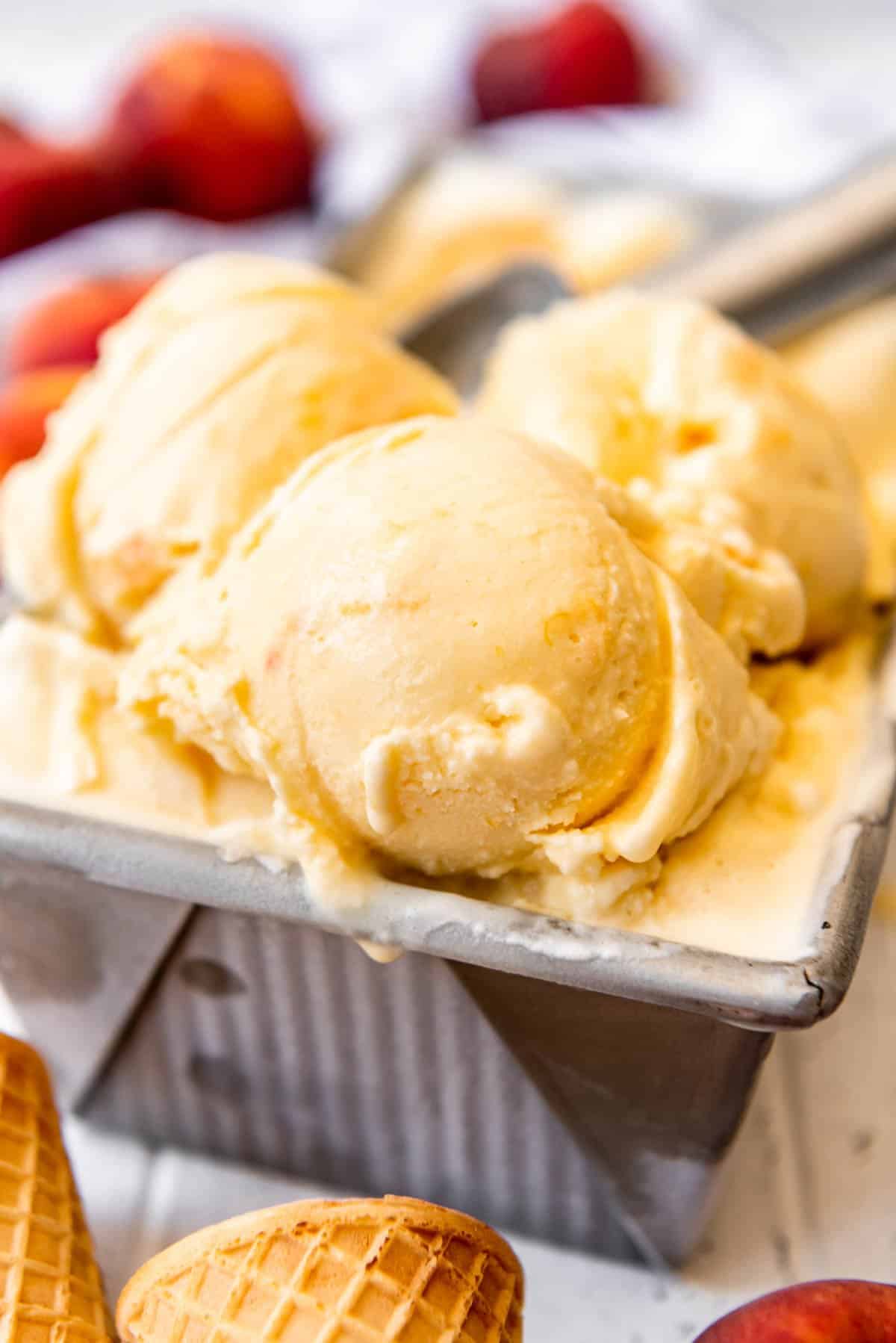 Scoops of homemade peach ice cream in a metal bread pan.