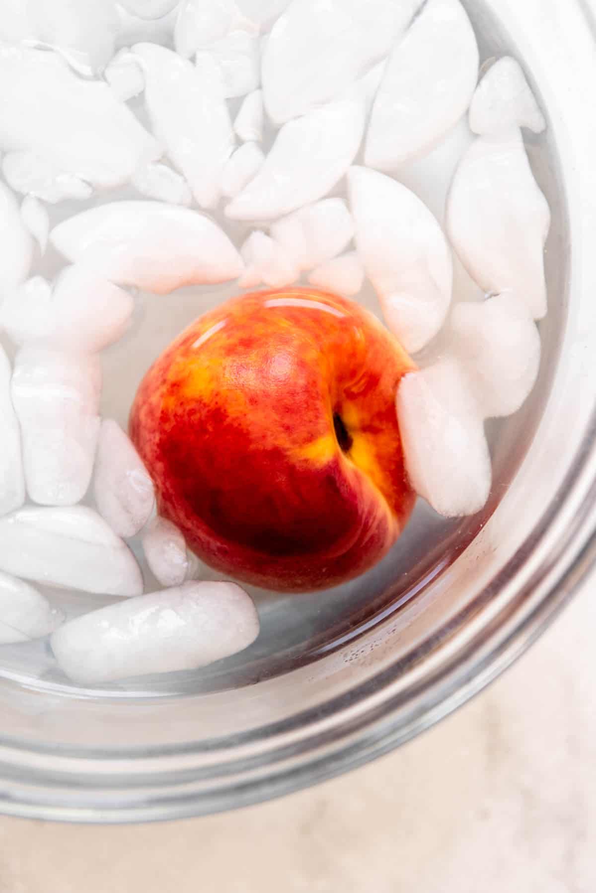 A blanched peach in an ice water bath to stop the cooking process.