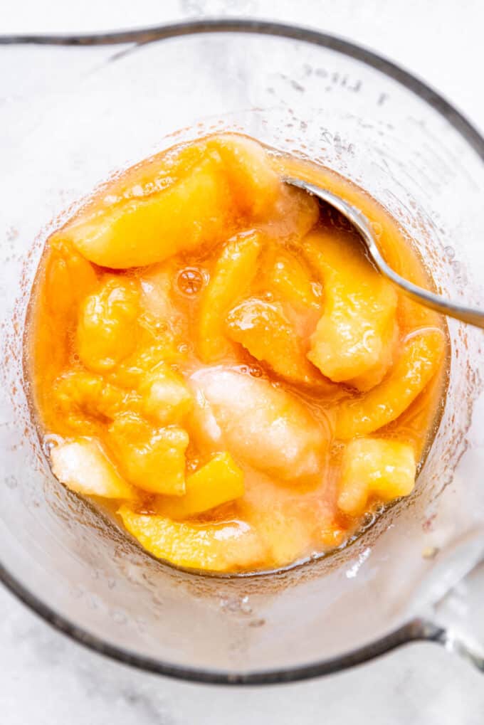 A bowl of sliced peaches with sugar to draw out the juices.