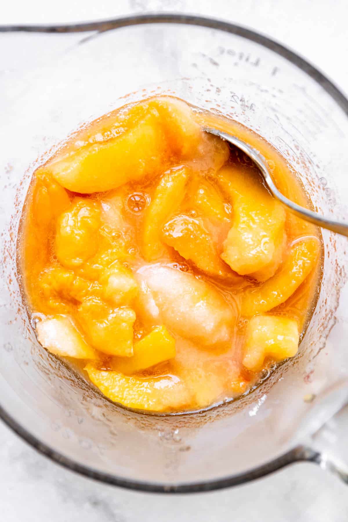 A bowl of sliced peaches with sugar to draw out the juices.