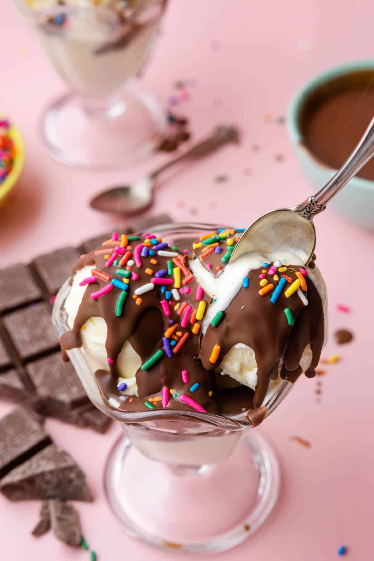 A spoon breaking through homemade chocolate magic shell topping over vanilla ice cream.