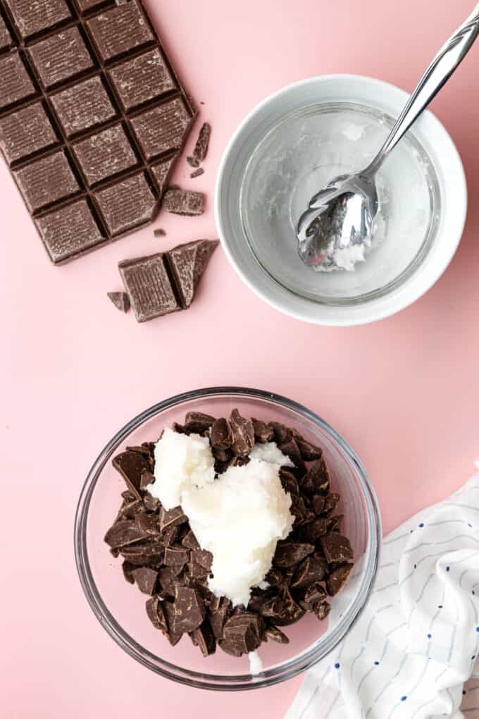 Adding coconut oil to chopped chocolate in a bowl.