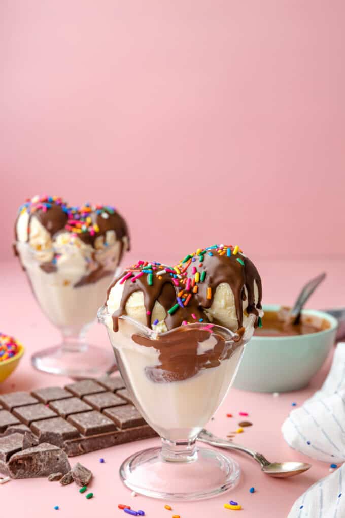 Two ice cream sundaes with magic shell in front of a bowl of homemade magic shell.