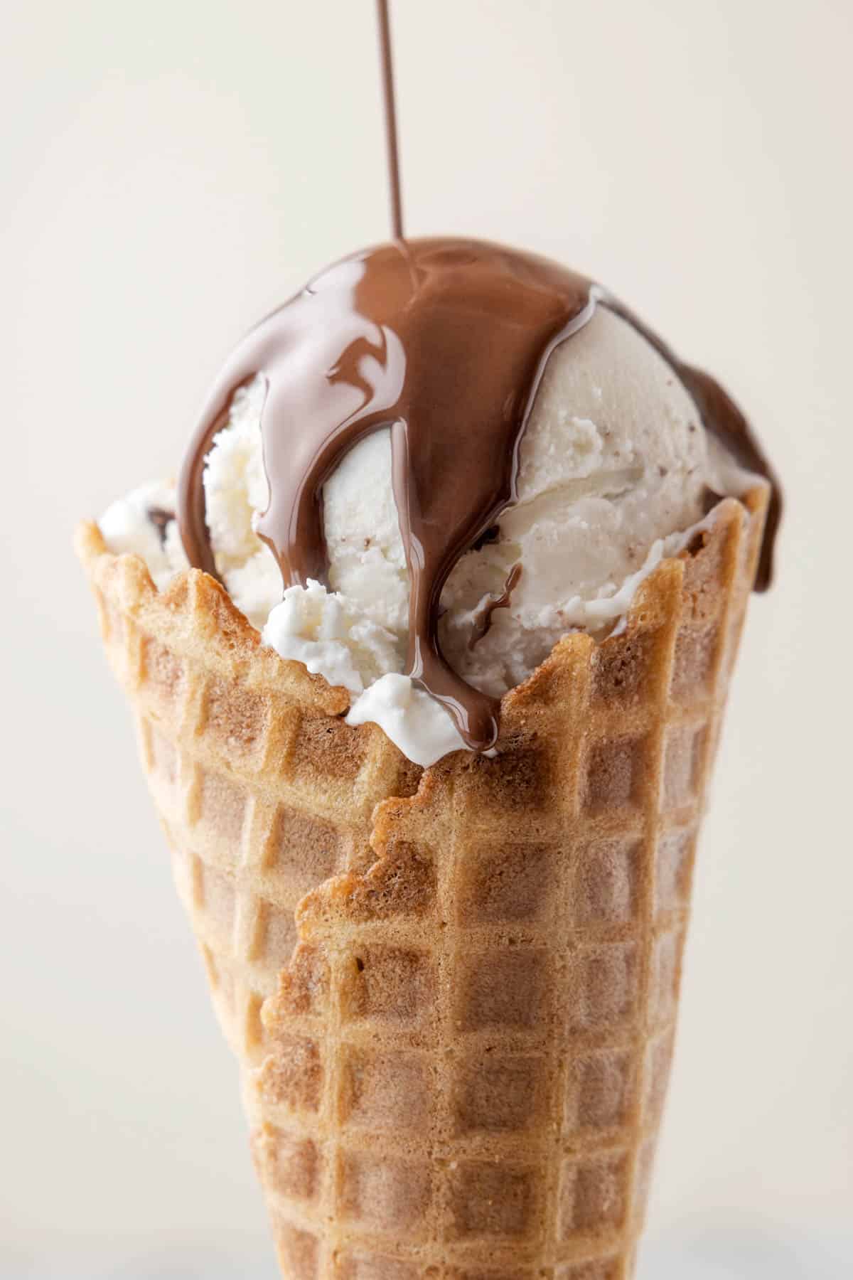 Drizzling mint chocolate magic shell topping over a scoop of ice cream.