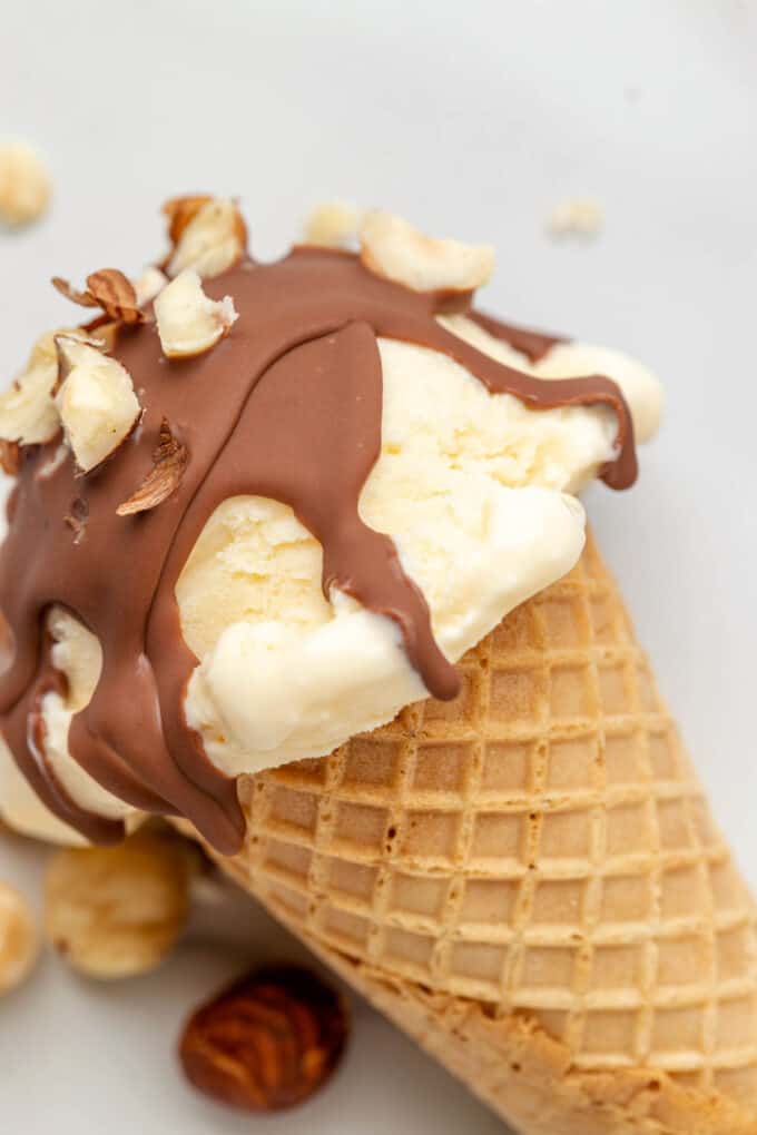 A close image of drips of Nutella magic shell on a vanilla ice cream cone.
