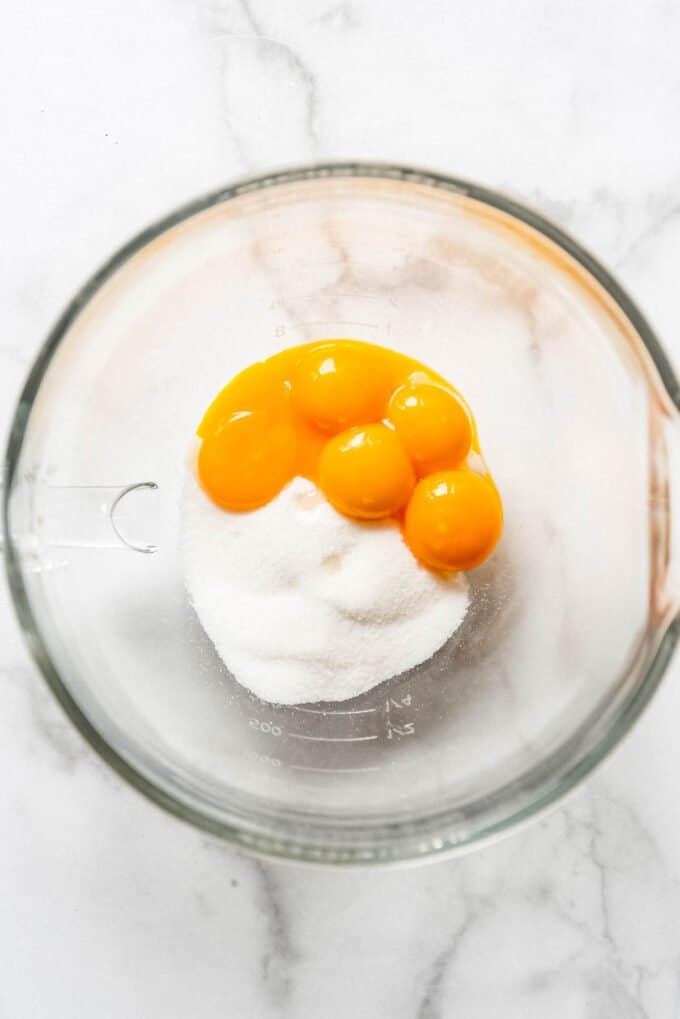 Egg yolks and granulated sugar in a bowl.