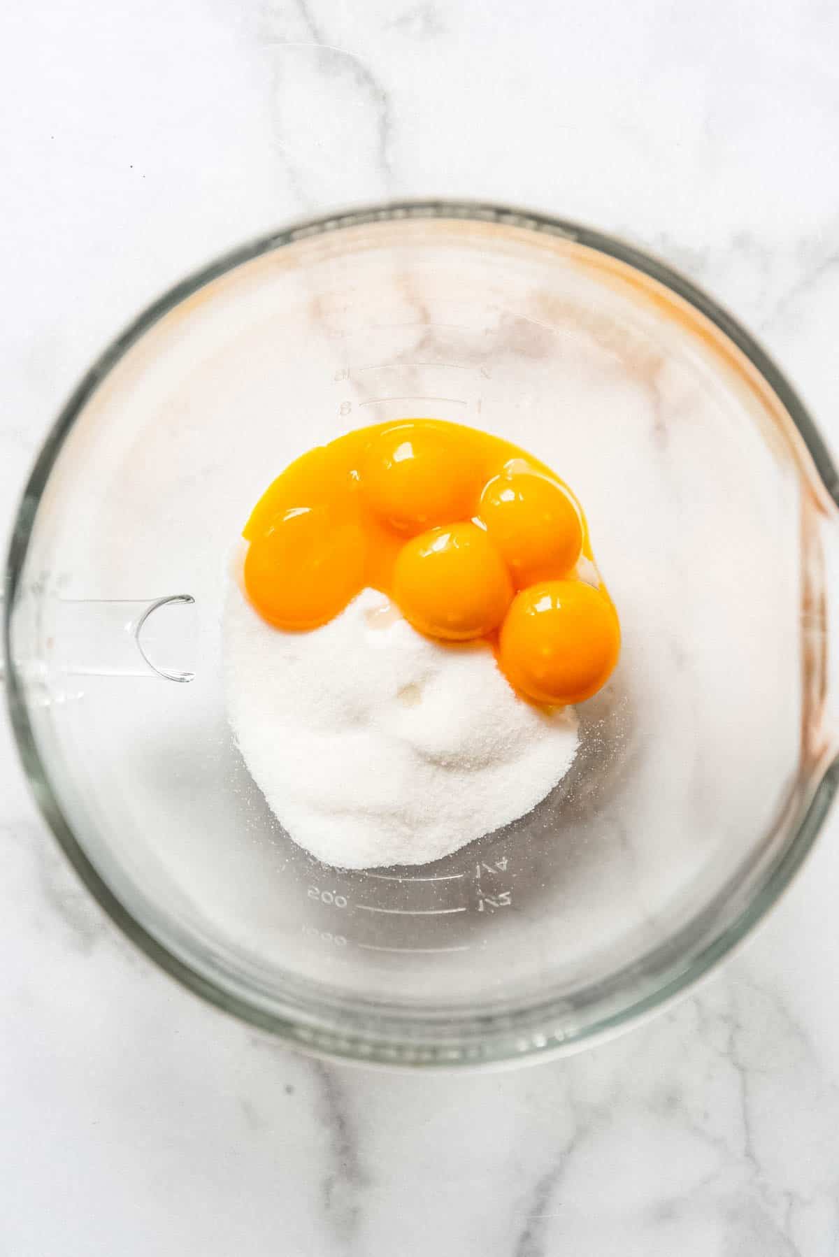 Egg yolks and granulated sugar in a bowl.