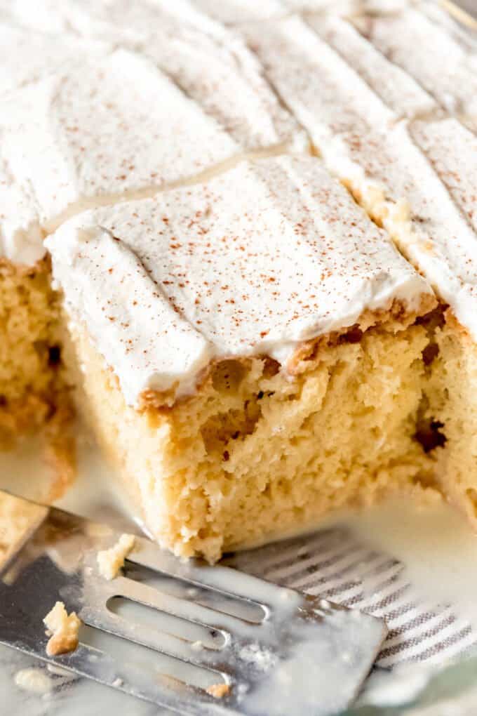 Tres leches cake sliced into square serving sized pieces with a spatula to the side.