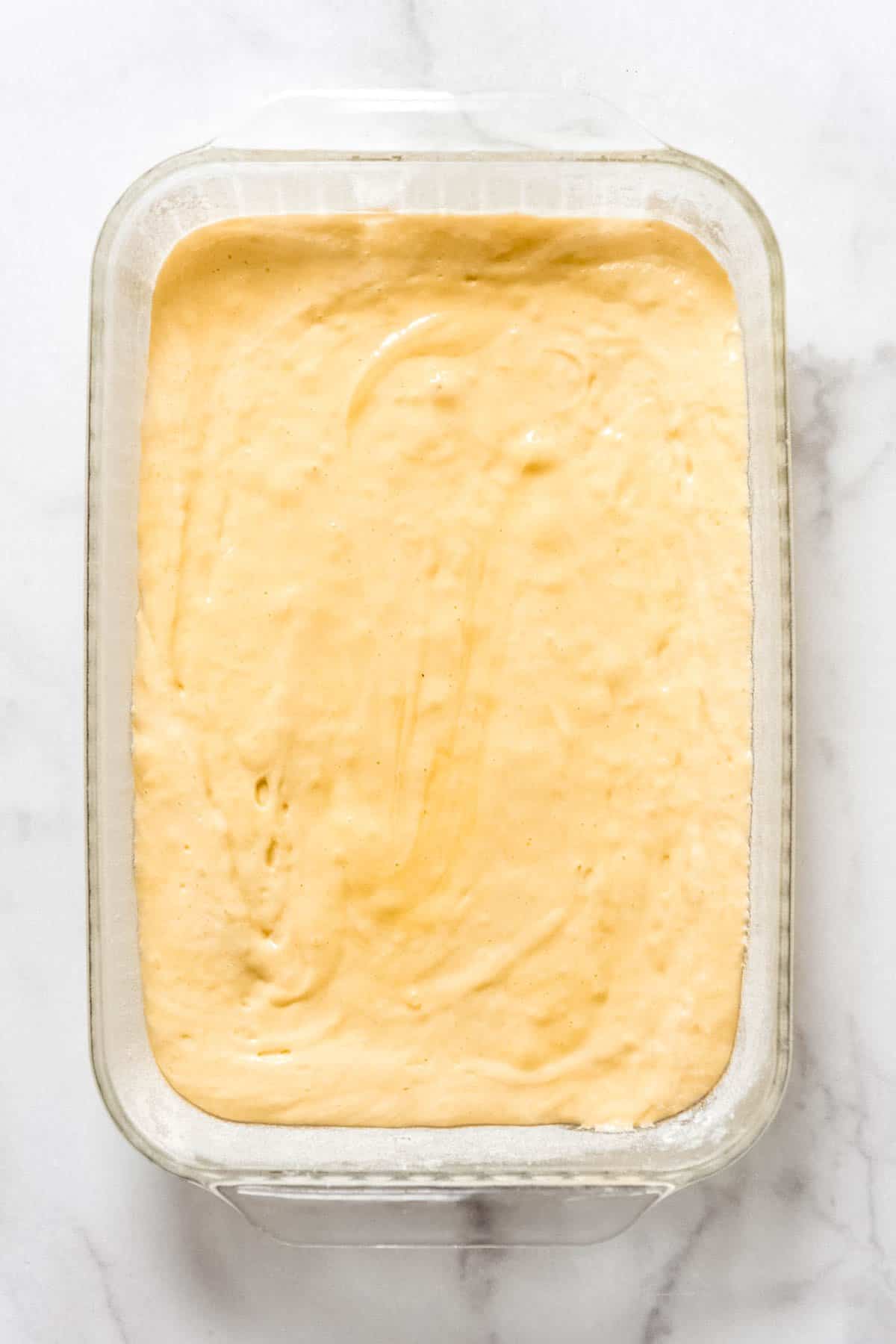 White sponge cake batter in a glass baking dish.