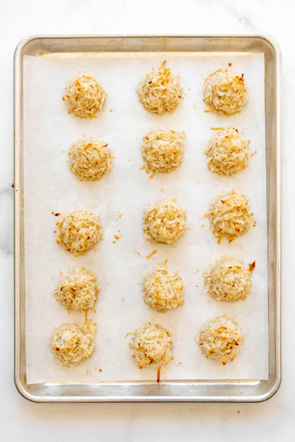 Baked coconut lime macarons on a baking sheet lined with parchment paper.
