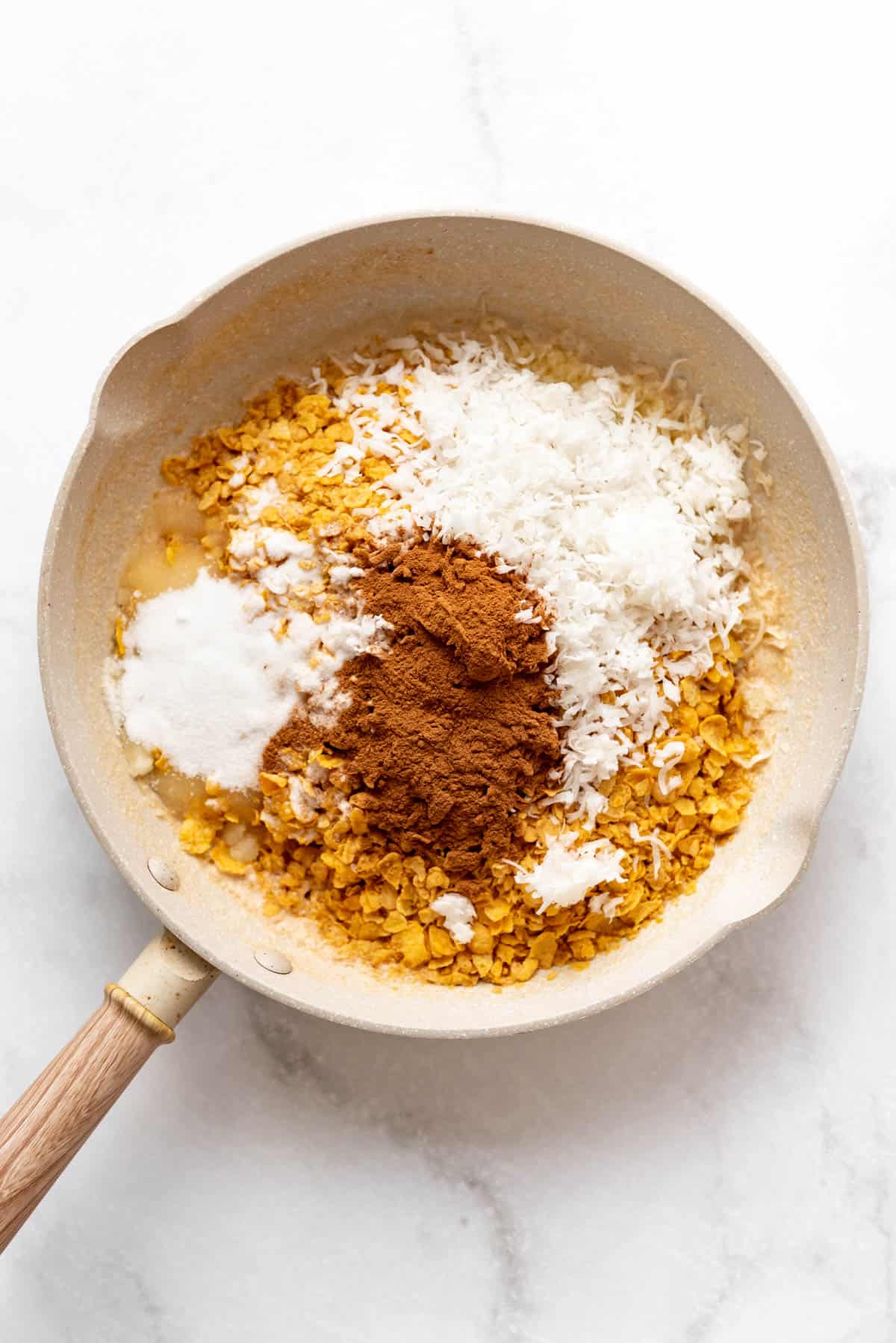 Melted butter, crushed cornflakes, sugar, cinnamon, and coconut in a skillet.