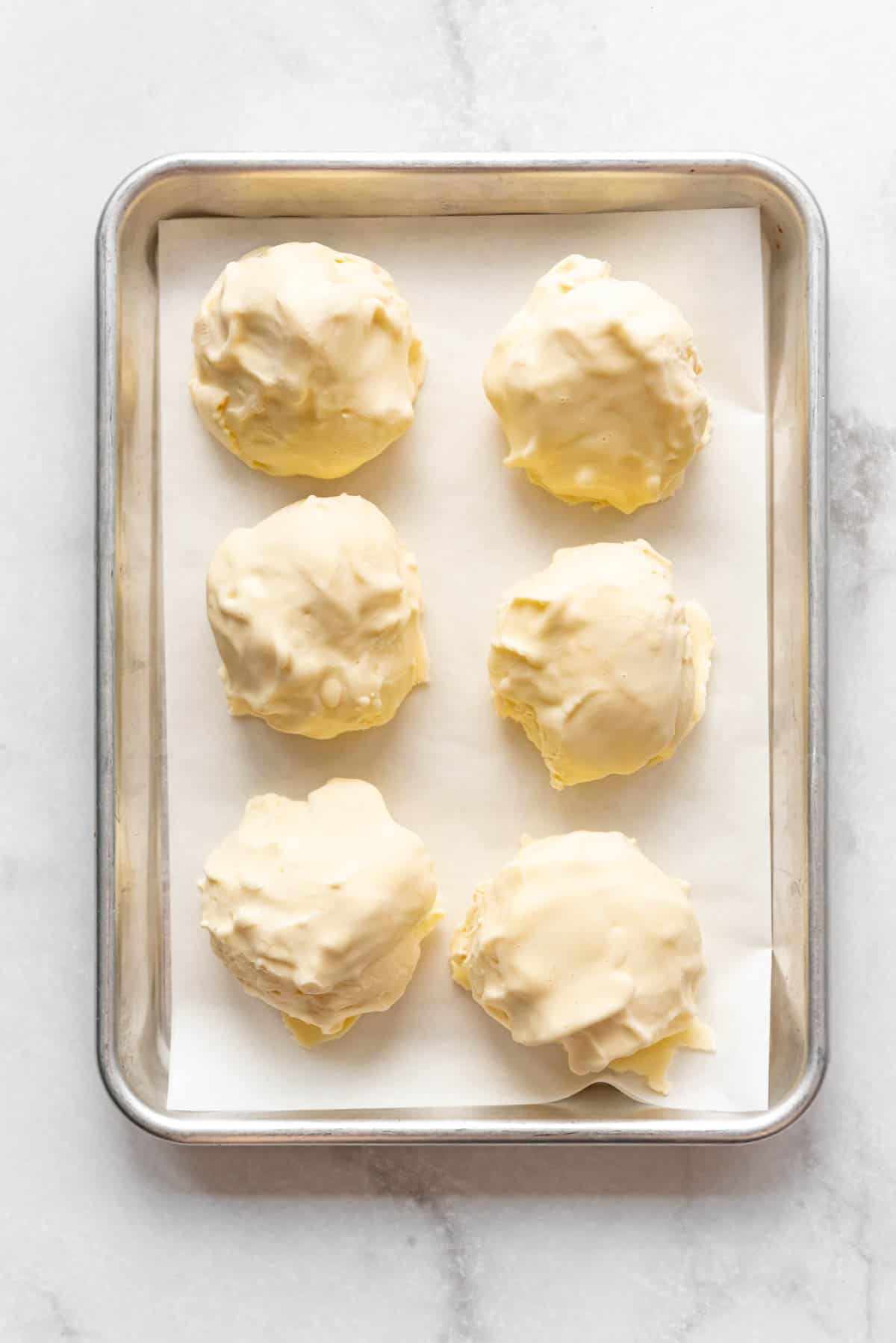 hard balls of scooped vanilla ice cream on a baking sheet.