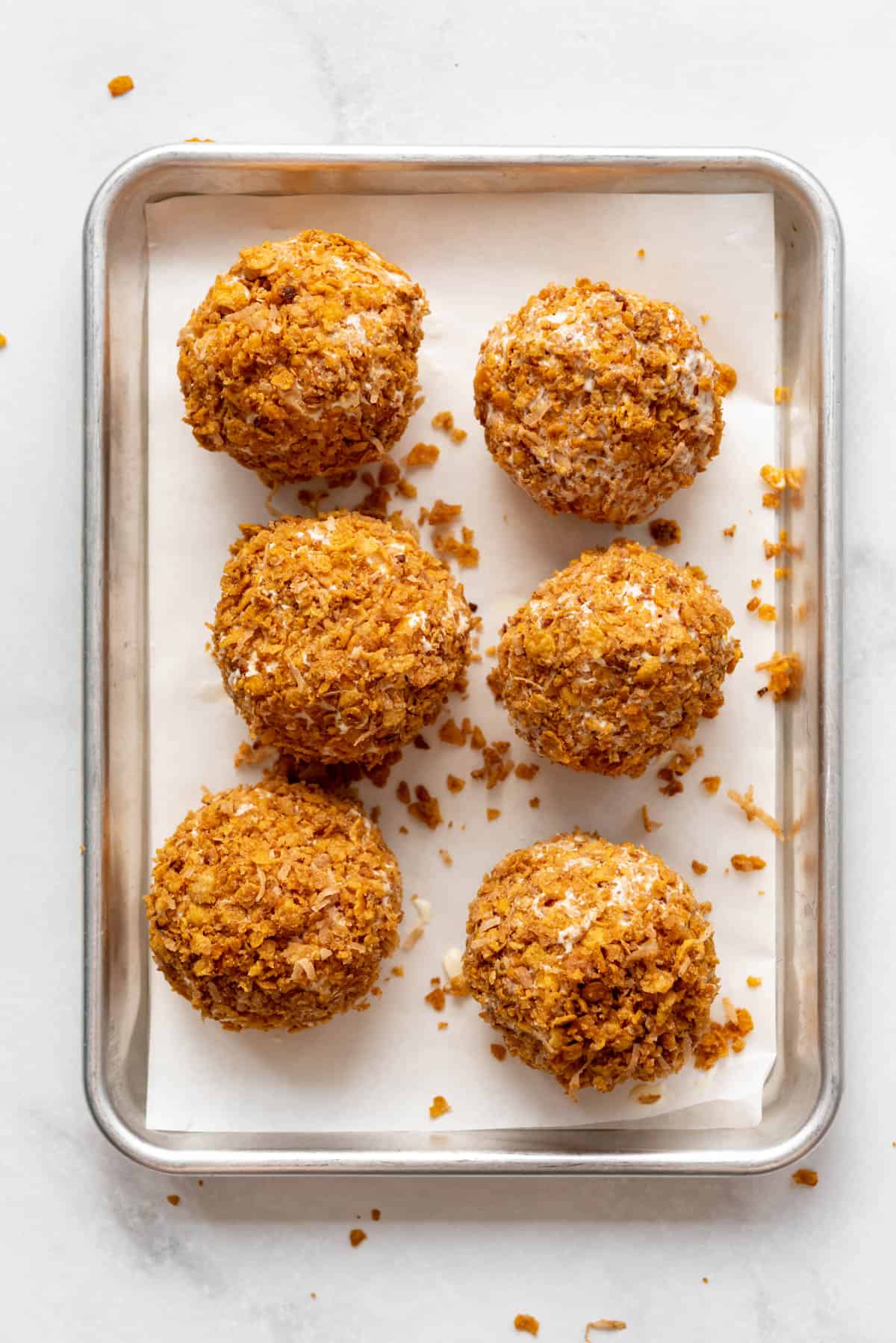 Six fried ice cream balls on a cookie sheet.
