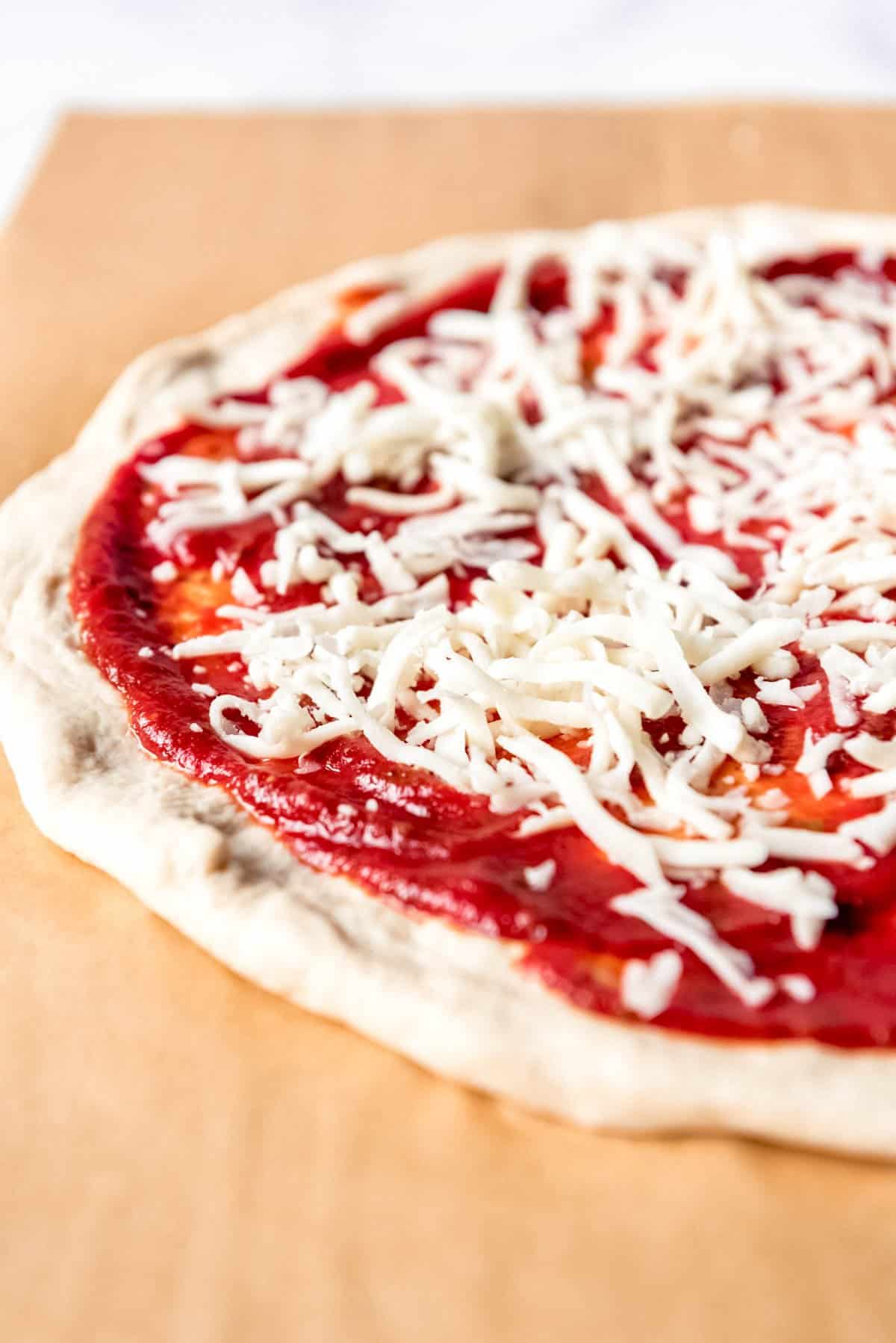 An image of a pizza topped with homemade tomato sauce and shredded mozzarella cheese.