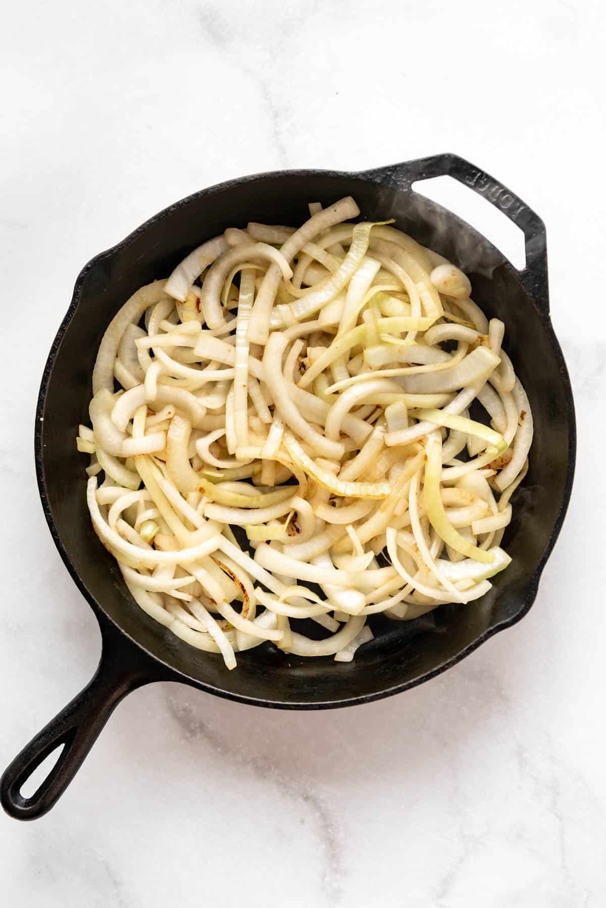 Sliced onions in a cast iron skillet.