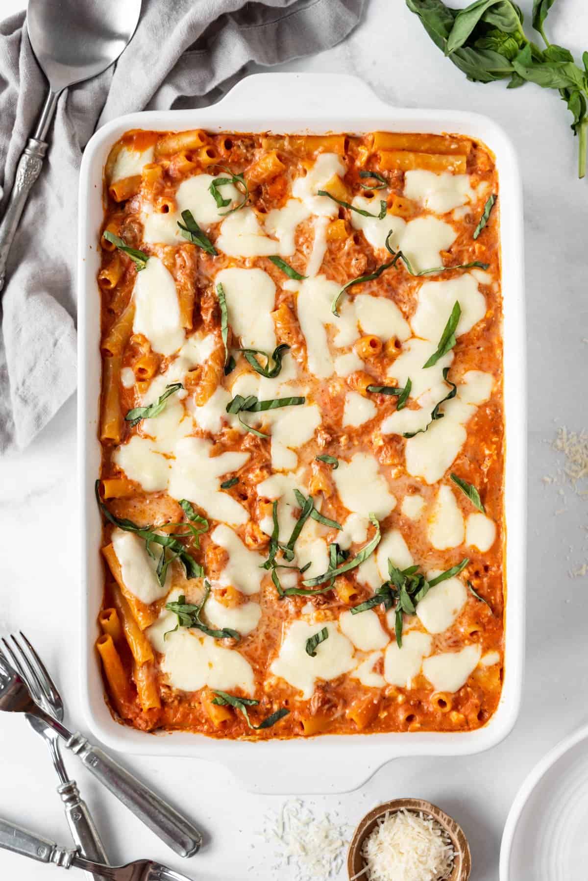 A large casserole dish of baked ziti with melted mozzarella cheese on top.