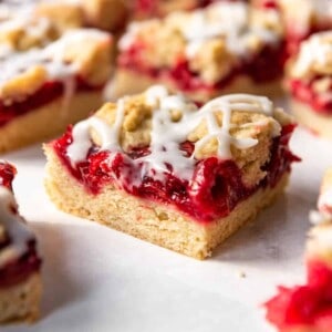 A cherry pie bar with shortbread cookie crust and glaze on top.
