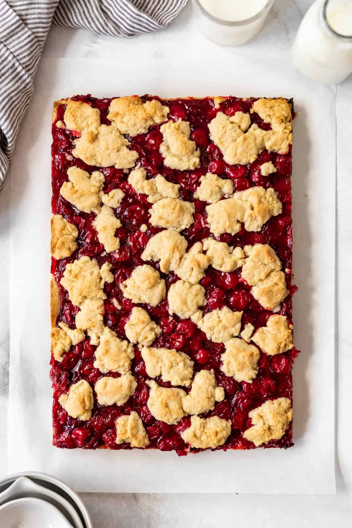 Baked cherry pie bars on parchment paper before adding the glaze.