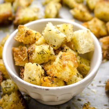 A small bowl filled with homemade croutons and surrounding by more croutons