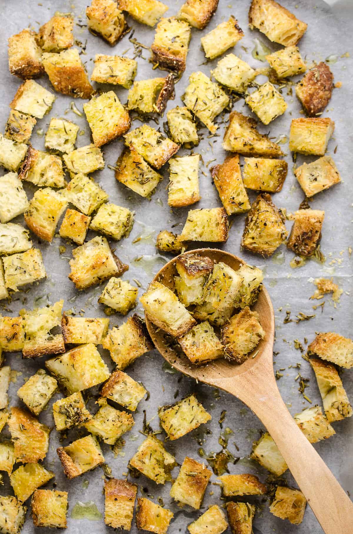 Homemade croutons on top of a cookie sheet lined with a piece of parchment paper