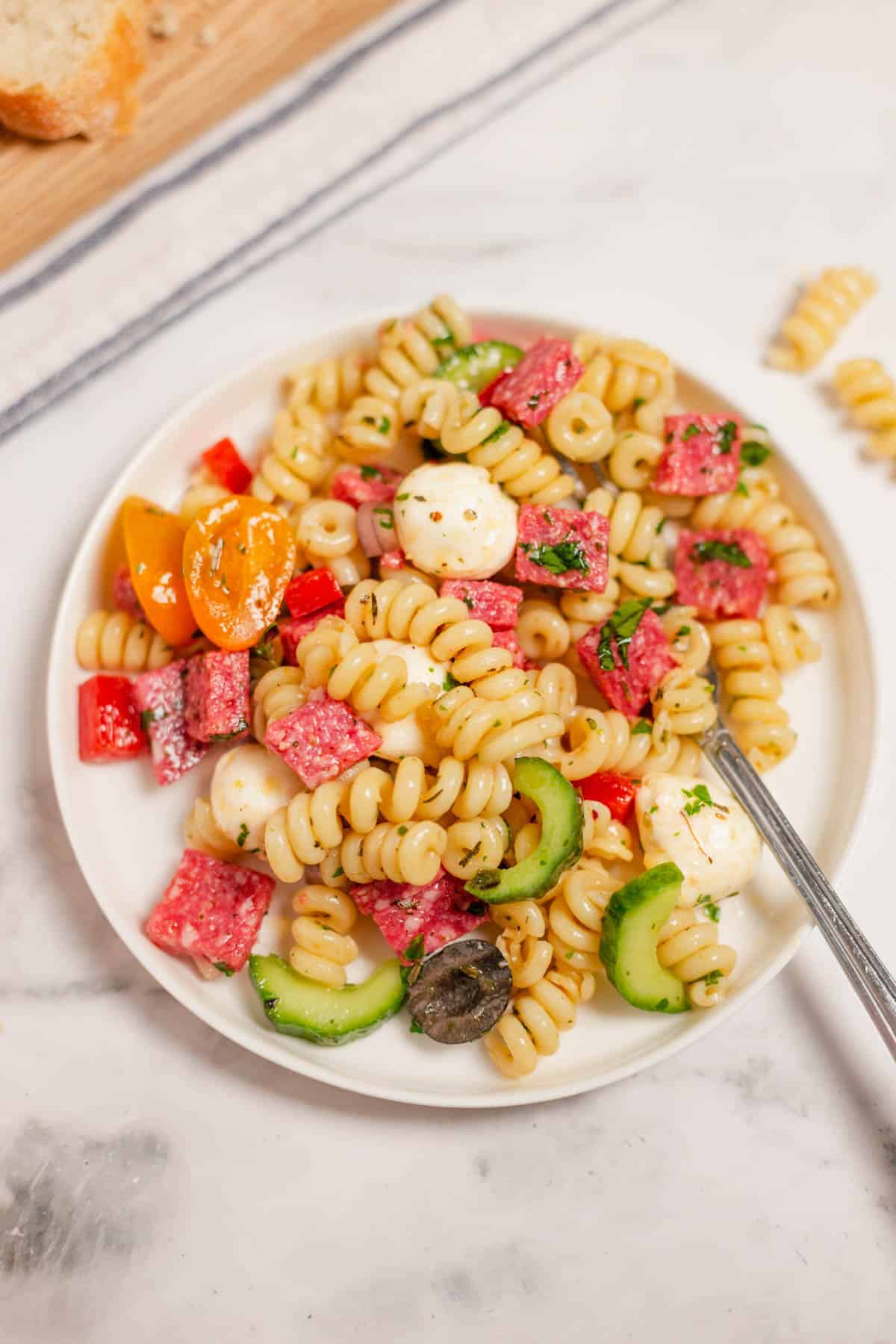 A plate of Italian pasta salad with a fork in it.