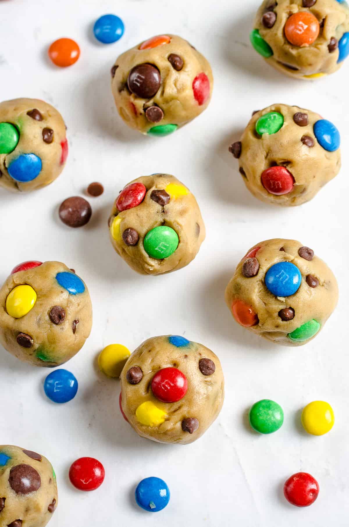 Nine balls of unbaked cookie dough on top of a plain white surface