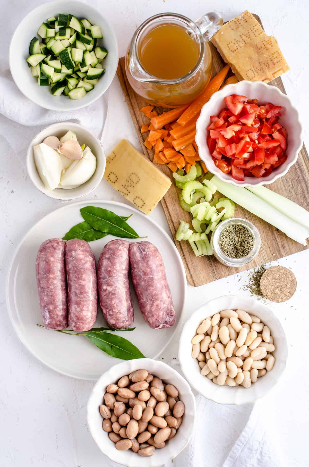 Chopped tomatoes, fresh garlic cloves, Italian sausage and the rest of the ingredients arranged on a kitchen countertop