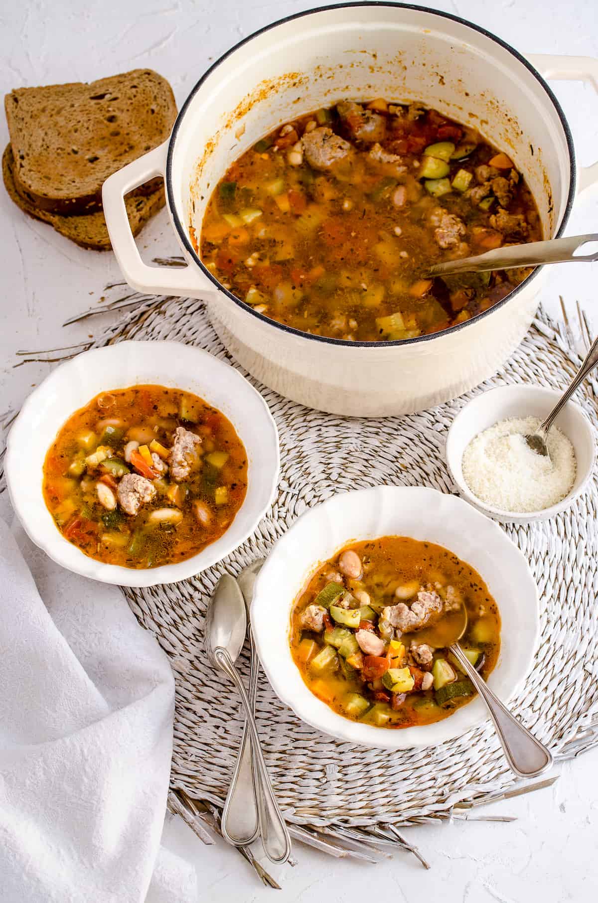 Two bowls of minestrone soup with the remaining soup in a nearby pot