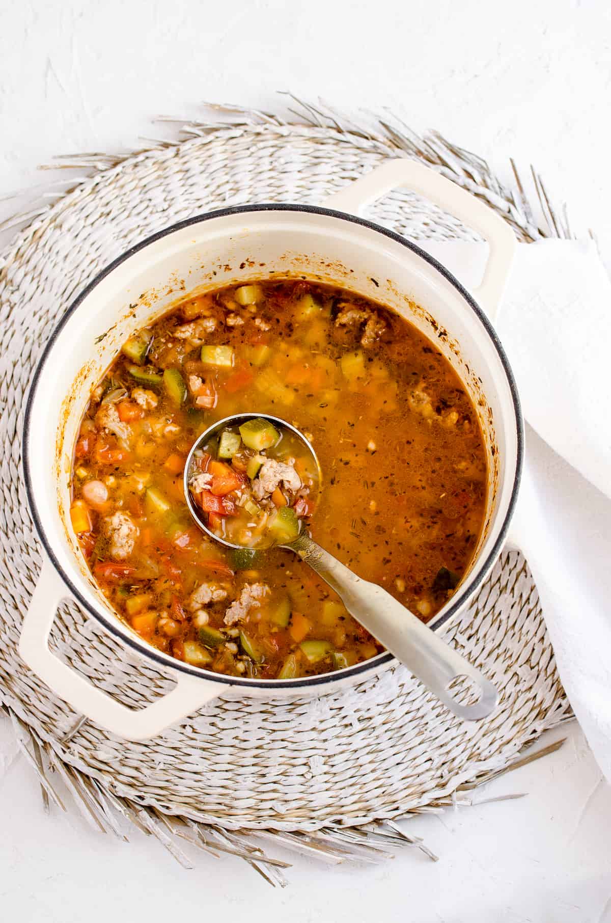 A pot full of homemade minestrone soup with a large ladle inside
